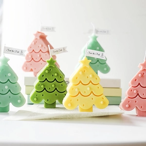 Group of colorful Christmas tree candles in green, pink and yellow pastel colors
