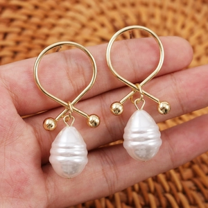 Detail showing vintage teardrop pearl earrings with golden crisscross ring design