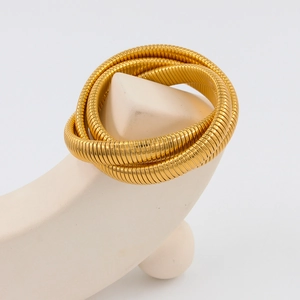 Detalle de una pulsera triple de acero dorado envuelta sobre soporte geométrico