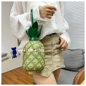 Detail of creative pineapple-shaped green crossbody bag featuring metallic rivets and texture