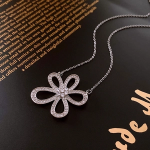 Vue macro d'un pendentif fleur argenté avec zircons posé sur un livre noir élégant