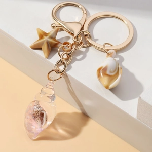 Detailed view of golden starfish and conch charms on a metal keychain with resin shell