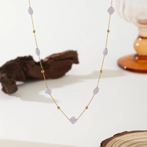 Detailed shot of golden stainless steel necklace with purple flower beads and pearls