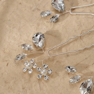 Close-up of handmade bridal hair pins with silver wire, pearls and sparkling rhinestones
