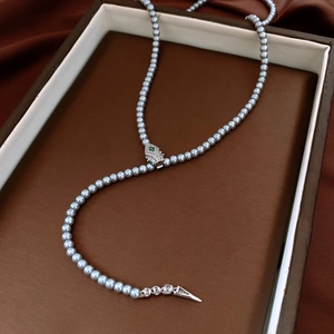 Detail of grey pearl necklace with a leopard head clasp and green gemstone eyes