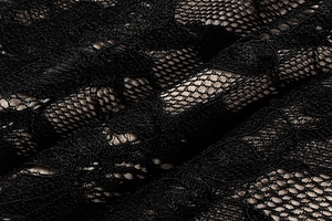 Detailed close-up of intricate floral black lace fabric with a soft mesh texture on the dress