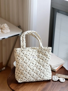 Gros plan d'un petit sac cabas en velours côtelé beige matelassé avec motifs de cœurs