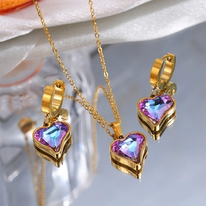 Macro shot of gold heart jewelry set with purple gradient crystals on a mirror