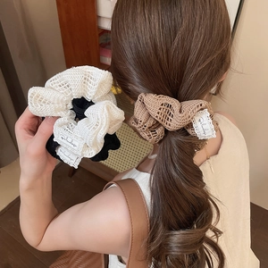 Détail de chouchous fleurs en maille crochetée en blanc, noir et marron café texturé