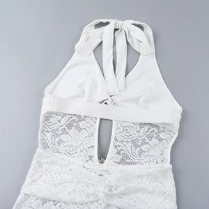 Détail d'une combinaison en dentelle blanche avec motifs floraux et encolure licou