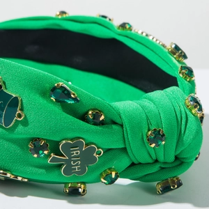 Macro detail of Irish headband with green crystals and gold clover charm with Irish text