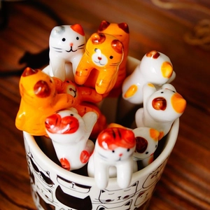 Hand-painted ceramic cat-shaped stirring spoons in a matching mug with warm lighting
