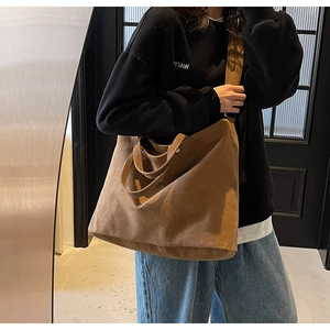 Detailed view of brown canvas tote bag texture and shoulder fit on model in lifestyle setting
