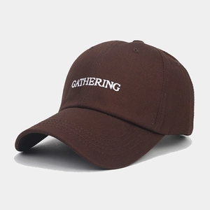 Gros plan de la broderie blanche GATHERING sur une casquette en coton marron