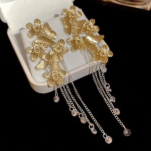 Macro shot of gold tassel earrings with hollow flowers and crystal butterfly details