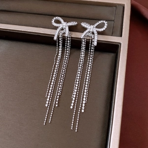 Detail view of silver bow earrings with zircon tassels on a jewelry display tray