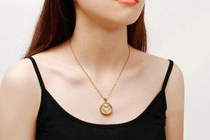 Detail of a gold double-layered heart pendant necklace on a neck model with white inlay