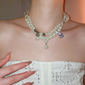 Detail einer zweilagigen Perlenkette mit lila Zirkonia-Tropfen und Silberakzenten