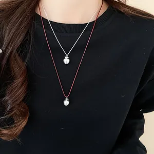 Detailed view of matte silver apple pendants with fine leaf design on dual layered chains