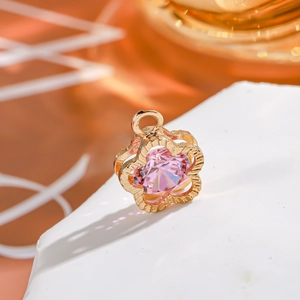 Close-up of a 14K gold flower pendant with a sparkling pink gemstone center detail