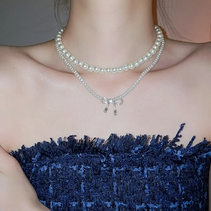 Close-up of double-layer pearl necklace with a sparkling bow pendant on neck