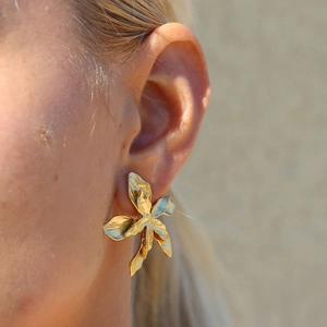 On-ear shot of luxury gold flower stud earrings in stainless steel for women