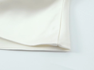 Close-up of white satin shirt showing smooth fabric texture and precise edge stitching
