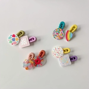Flat lay of colorful acrylic hair clips with floral, rainbow, and checkerboard patterns