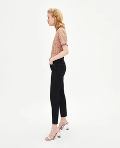 Vista laterale dell'elegante top in pizzo marrone chiaro e jeans neri slim fit