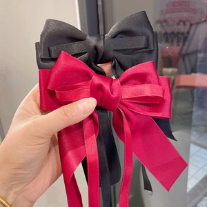 Elegant satin bow hair clip with long streamers in classic red and black colors