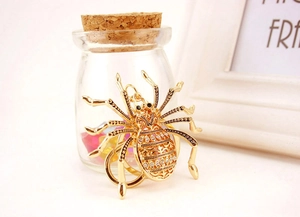 Close-up of golden spider metal keychain with green gems and inlaid clear rhinestones