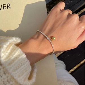 Detail of S925 sterling silver heart bracelet worn on wrist with cozy sweater background