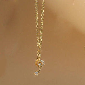 Macro shot of gold treble clef musical note pendant necklace with white zircon stones