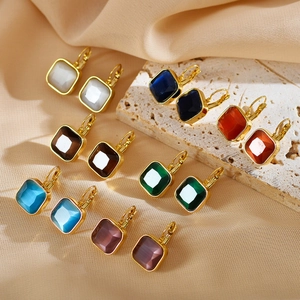 Macro shot of colorful square gemstone drop earrings with gold plating on textured fabric