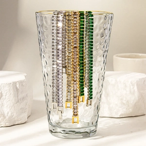 Detail of 18K gold and silver tennis bracelets with emerald stones in prong setting