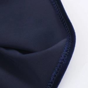 Close-up of deep blue ribbed velvet fabric showing detailed overlock stitching and texture