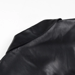 Détail du col à revers et de l'épaule sur une robe noire en similicuir PU de qualité
