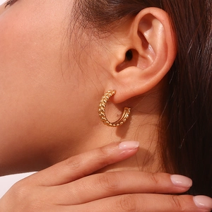 Close-up of 18K gold-plated braided hoop earring showing texture on model ear