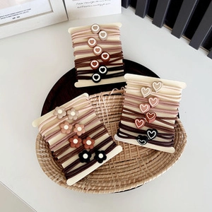 Close-up of heart and flower hair ties in brown and khaki tones on a bamboo tray