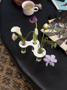 Macro detail of acrylic wave base vase with glass test tubes and fresh flowers
