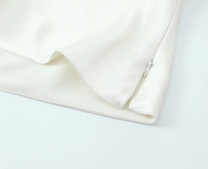 Detailed macro view of the invisible zipper and fine stitching on white satin blouse