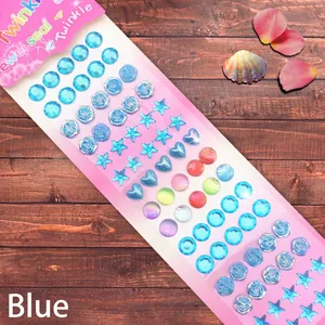 Detail of 3D crystal jewel stickers with blue stars, hearts and shell shapes on wood