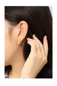 Close-up of minimalist gold U-shape drop earrings and thin double band ring on model