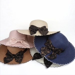 Detail of five colored straw sun hats with wavy lace edges and striped bow ribbons