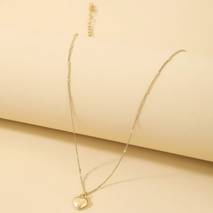 Detailed close-up of golden heart pendant necklace with decorative disc chain and smooth finish