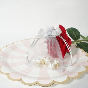 Macro shot of silver organza drawstring gift bag with pearls on a decorative petal dish
