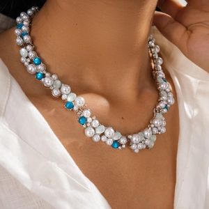 Close-up of pearl and blue gemstone layered necklace on model with white linen shirt