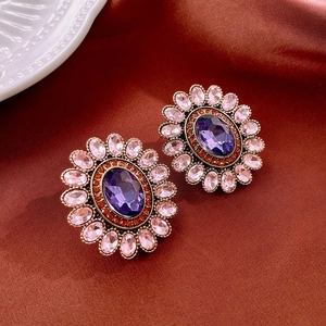 Close-up of vintage flower earrings with purple and pink crystals on brown silk