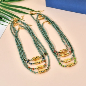 Detail view of turquoise beaded necklaces with gold-plated evil eye pendant and charms