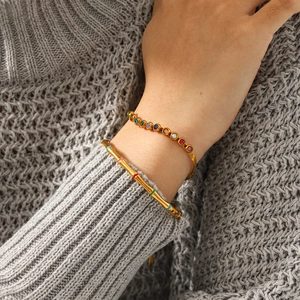 Detail of 18k gold bamboo enamel bangle and colorful zircon chain on a model sweater
